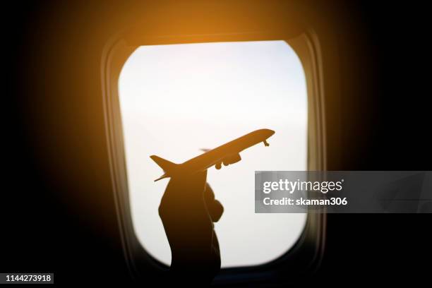 female passenger play small airplane near window seat - raamplaats stockfoto's en -beelden