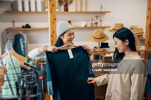 小売店店員は、ブティックで衣類のためのミッドアダルト女性顧客の店を支援 - customer satisfaction ストックフォトと画像