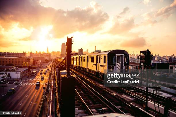 ニューヨークの地下鉄列車はクイーンズで駅のプラットフォームに近づいて - 通勤電車 ストックフォトと画像
