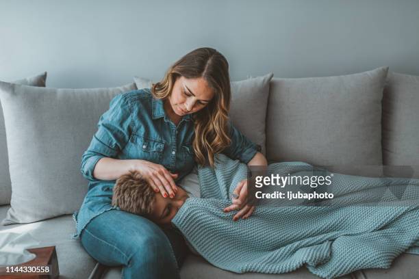 sick boy laying in bed and mother hand taking temperature - headache imagens e fotografias de stock