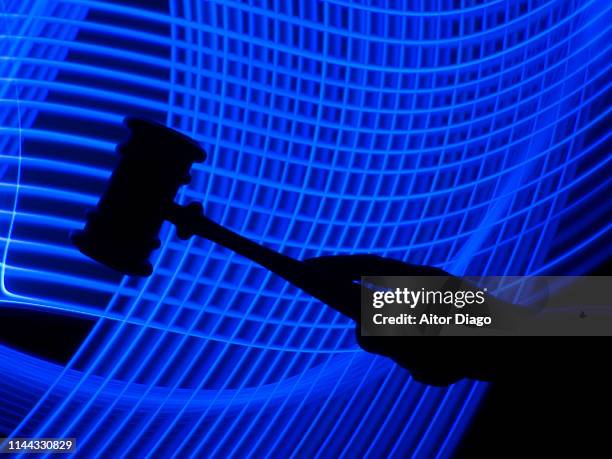 hand holding a judge's hammer in a futuristic environment - lady justice technology stock pictures, royalty-free photos & images