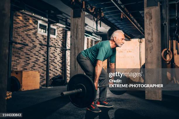 homme aîné actif effectuant un exercice de deadlift dans un gymnase de crossfit - entraînement-aux-haltères photos et images de collection