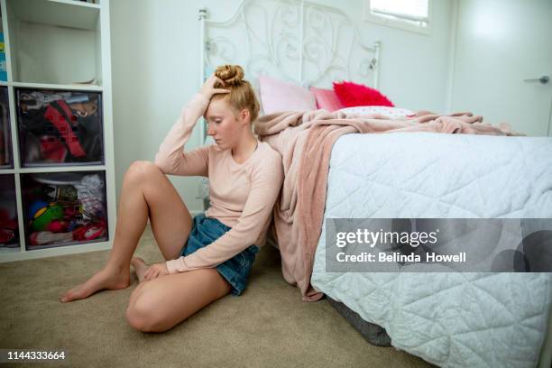 teenage girl in her bedroom on devices, showing a range of emotions including happiness and saddness. - jugendzimmer stock-fotos und bilder