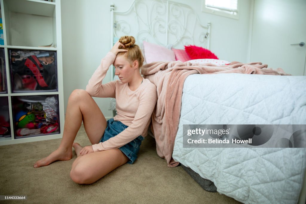 Teenage girl in her bedroom on devices, showing a range of emotions including happiness and saddness.