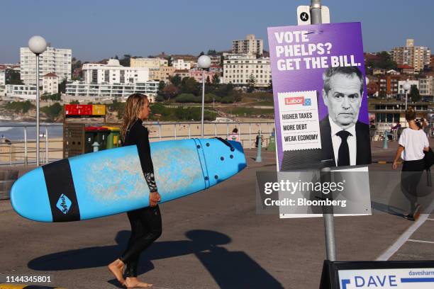 Surfer walks past a campaign poster for independent candidate Kerryn Phelps at Bondi Beach in Sydney, Australia, on Saturday, May 18, 2019. Prime...