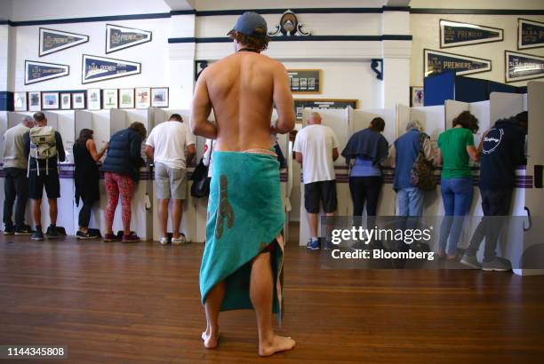 Voter dressed in swimwear wait in line as other voters cast their ballots at a polling station during a federal election in Sydney, Australia, on...