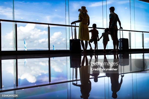 rear view of a family looking through window from the airport. - family airport stock pictures, royalty-free photos & images