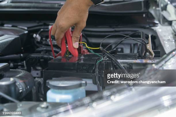 automotive mechanic uses battery jumper cables for chargers and jump starters a dead battery, maintenance car battery concept. - image - car battery stock pictures, royalty-free photos & images