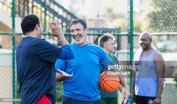 group of men having fun on basketball court - mature men playing basketball stock pictures, royalty-free photos & images