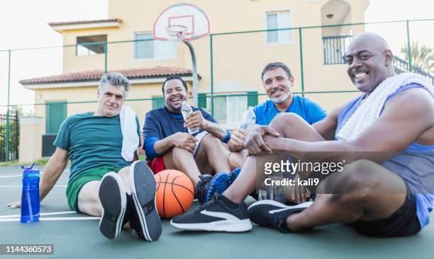 group of men hanging out on basketball court, resting - mature men playing basketball stock pictures, royalty-free photos & images