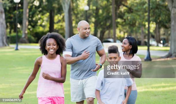famille interracial avec deux enfants marchant dans le parc - black shorts photos et images de collection