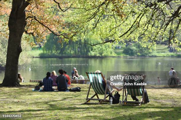 People relax and enjoy the sunshine in deck chairs by the lake in St James's Park on April 22, 2019 in London, England. This Easter weekend has...