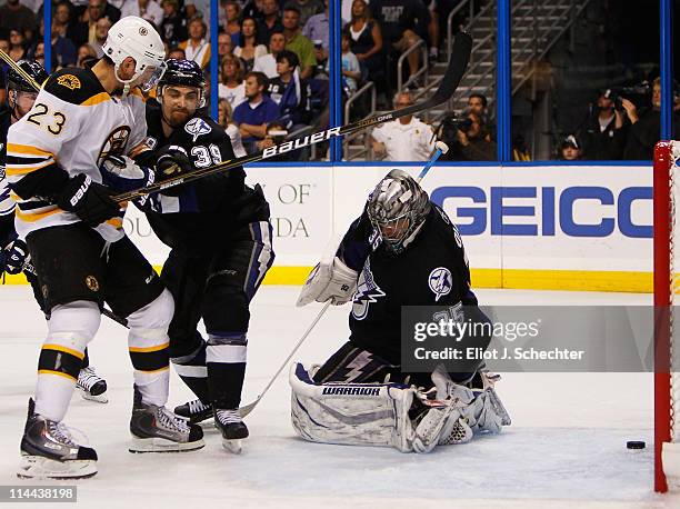 Dwayne Roloson, Mike Lundin of the Tampa Bay Lightning and Chris Kelly of the Boston Bruins watch as a puck shot by Tyler Seguin of the Boston Bruins...