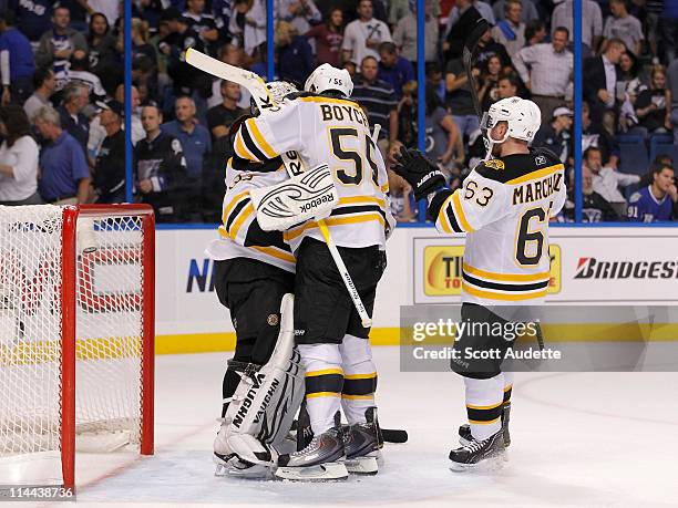 Tim Thomas of the Boston Bruins celebrates with teammates Johnny Boychuk and Brad Marchand after winning against the Tampa Bay Lightning in Game...