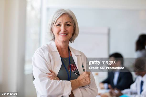 un alegre médico femenino se detiene para una foto - lab coat fotografías e imágenes de stock