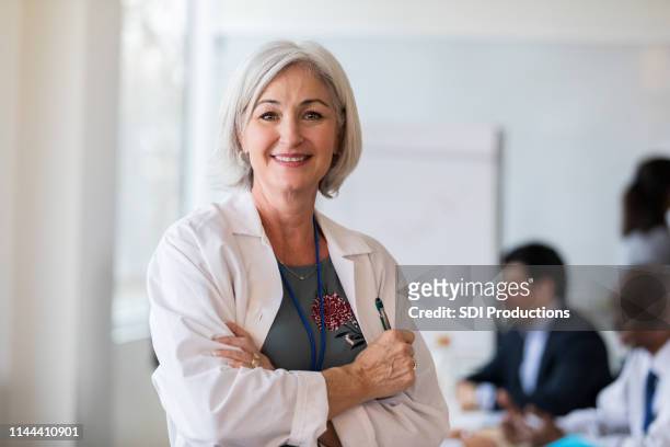a cheerful mature female doctor stops for a photo - businesswear stock pictures, royalty-free photos & images