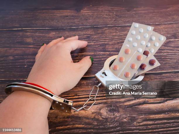 a person chained with shackles to a pile of pills - slaappil stockfoto's en -beelden