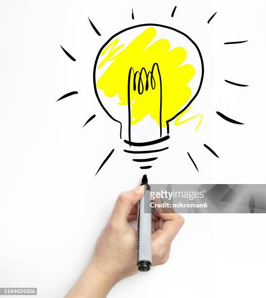 hand drawing a light bulb on white page with marker - marker pen stock-fotos und bilder