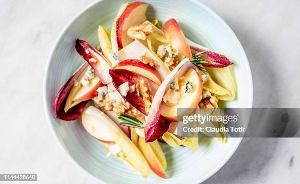 a bowl of endive salad with slices of apple, walnuts, and blue cheese on white background - chicory stock pictures, royalty-free photos & images