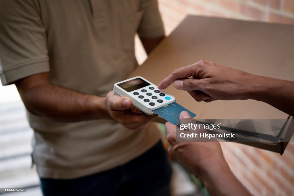 Unrecognizable customer paying for his pizza delivery at home with credit card