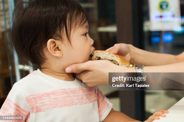 a baby boy is being fed by his mother with a sandwich - toddler eating sandwich stock pictures, royalty-free photos & images