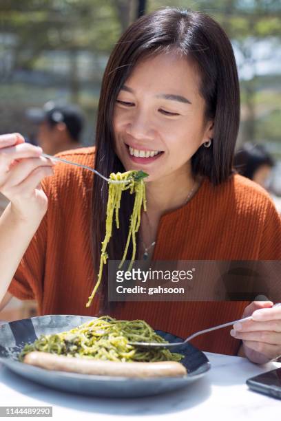 happy asian woman eating yummy and healthy pesto spaghetti at restaurant - pesto imagens e fotografias de stock