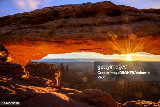 view through arch mesa arch at sunrise with sunstar, colorado river canyon with the la sal mountains behind, view at grand view point trail, island in the sky, canyonlands national park, moab, utah, usa - island in the sky stock pictures, royalty-free photos & images