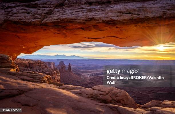 view through arch mesa arch at sunrise, colorado river canyon with the la sal mountains behind, view at grand view point trail, island in the sky, canyonlands national park, moab, utah, usa - mesa arch stock pictures, royalty-free photos & images