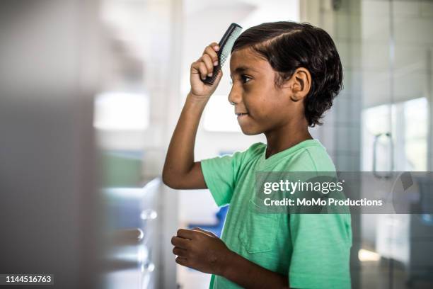 boy combing his hair in the mirror - combing fotografías e imágenes de stock