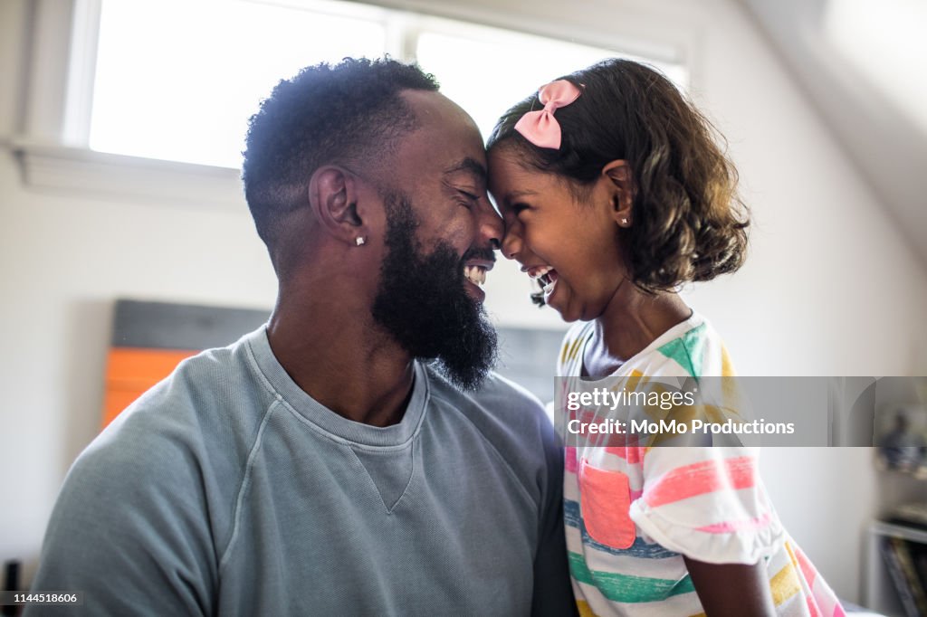 Father and daughter laughing in bedroom