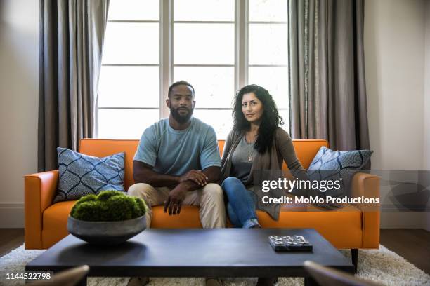 portrait of husband and wife in living room - ritratto coppia mista foto e immagini stock