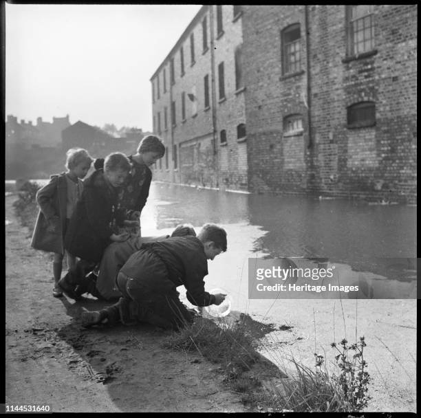 Children using a goldfish bowl to fish in the Caldon Canal, Hanley, Stoke-on-Trent, 1965-1968. Howson's Eastwood Sanitary Ware Works on Clifford...