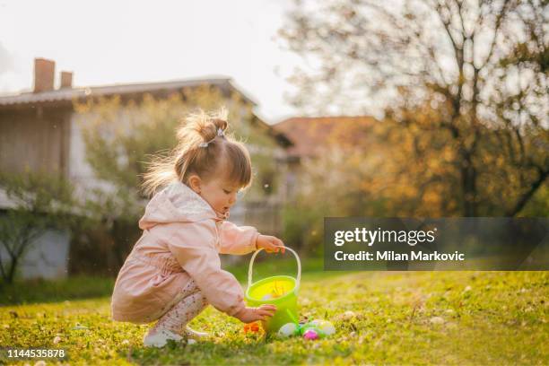jugando en el césped junto a la casa durante la pascua - egg hunting fotografías e imágenes de stock