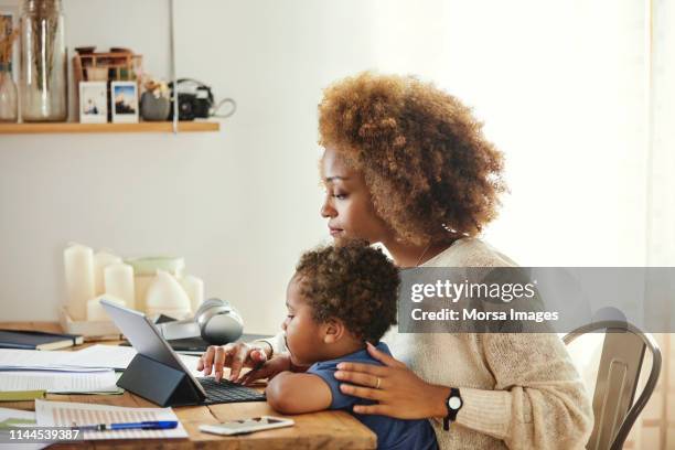 madre con figlio che lavora su tablet digitale a casa - madre capofamiglia foto e immagini stock