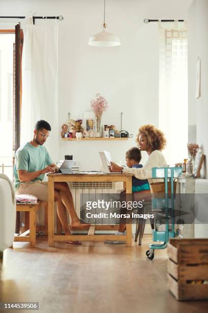 parents working while sitting with son at home - telecommuting couple stock pictures, royalty-free photos & images