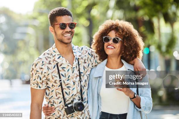 couple walking arm around on sidewalk in city - walking toward camera stock pictures, royalty-free photos & images