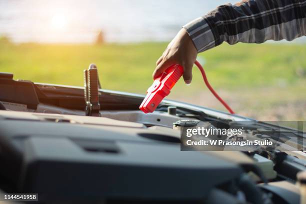 close-up of mechanic attaching jumper cables to car battery - car jumper leads stock pictures, royalty-free photos & images