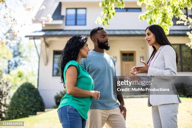 couple meeting with real estate agent in front of home - real estate agent stock pictures, royalty-free photos & images