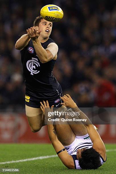 Marc Murphy of the Blues handballs whilst being tackled by Allen Christensen of the Cats during the round nine AFL match between the Carlton Blues...