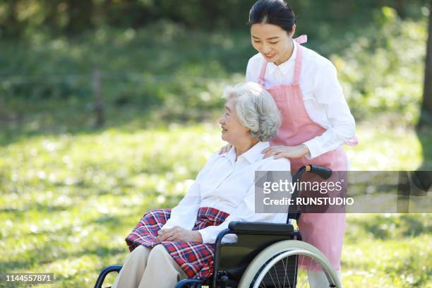 caregiver assisting senior woman in wheelchair - volunteer aged care stock pictures, royalty-free photos & images