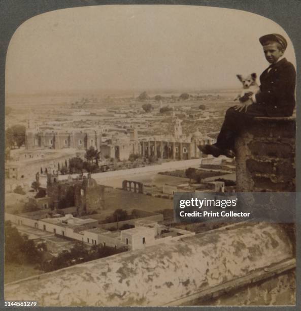 From San Francisco Cathedral, on the largest Aztec Pyramid, looking over Cholula, Mexico', 1901. A boy and his dog perched high on the Iglesia de...