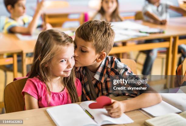 l’écolier mignon embrassant son premier amour dans la salle de classe. - young boy and girl in love photos et images de collection