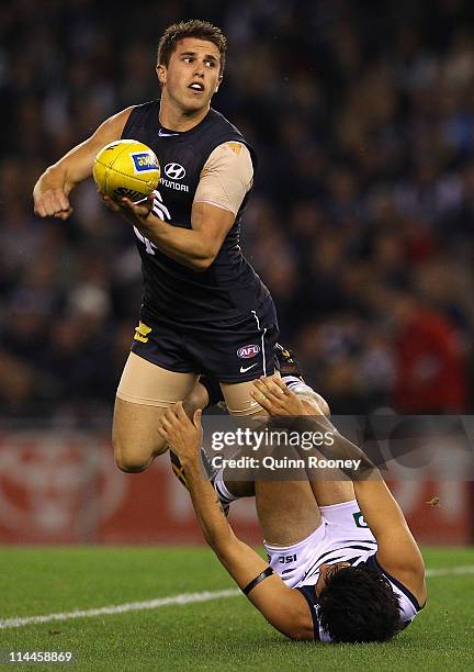 Marc Murphy of the Blues handballs whilst being tackled by Allen Christensen of the Cats during the round nine AFL match between the Carlton Blues...