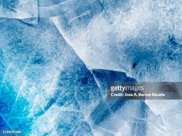 full frame of the textures formed of a block of cracked ice on a blue and white color background. - ice texture foto e immagini stock