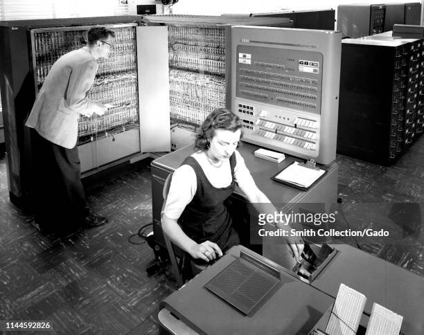 Employees working with IBM type 704 electronic data processing machine used for making computations for aeronautical research at Langley Research...
