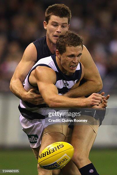 Joel Selwood of the Cats handballs whilst being tackled by Bryce Gibbs of the Blues during the round nine AFL match between the Carlton Blues and the...