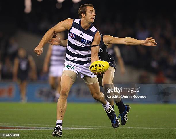 Joel Corey of the Cats handballs whilst being tackled during the round nine AFL match between the Carlton Blues and the Geelong Cats at Etihad...