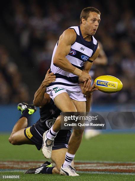 David Wojcinski of the Cats handballs whilst being tackled during the round nine AFL match between the Carlton Blues and the Geelong Cats at Etihad...