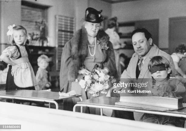 Italian educationist and founder of the Montessori Schools, Maria Montessori and her nephew watching a girl working in a classroom in Acton, London,...