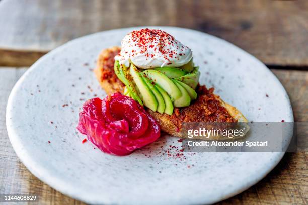 close-up of avocado toast with salmon and poached egg on a plate - pochiert stock-fotos und bilder